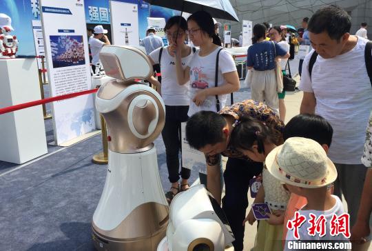 图为观众对咨询机器人产生兴趣。 向一鹏 摄